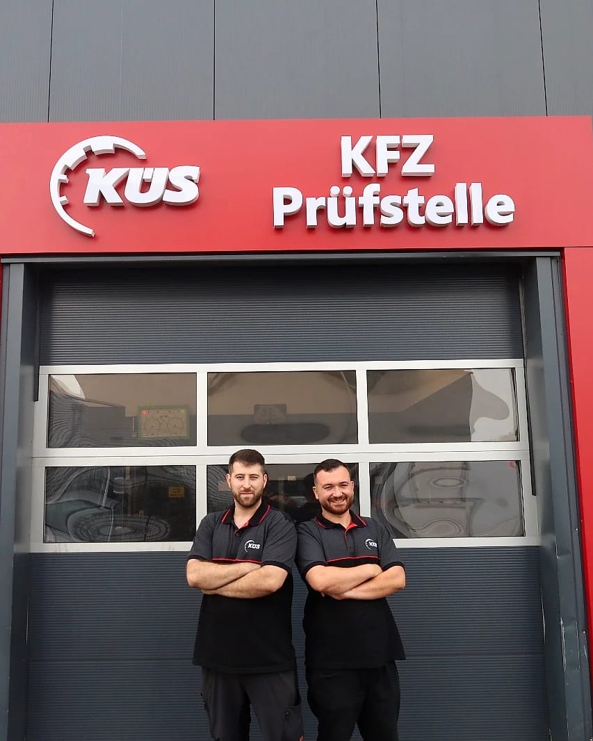 Inhaber der KÜS-Prüfstelle Köln-Mülheim Inhaber Ahmed Arslan (links) und Baran Kargin (rechts) vor dem KÜS-Schild der Prüfstelle in Köln-Mülheim